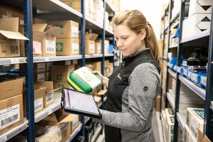 Tammed Oy. Nainen tarkistaa tuotteen tietoja varaston käytävällä.
