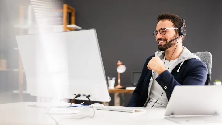 Kuvituskuva: Mies istuu toimistopöydän ääressä ja juttelee asiakkaalleen kuulokkeiden kautta.