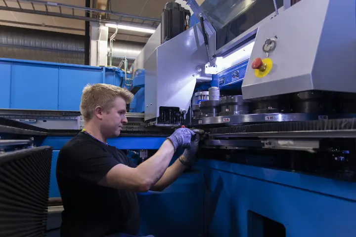 Ouneva Oy:n työntekijä huoltaa tehtaan konetta.